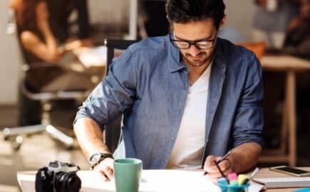 Yrittäjä työpöydän ääressä selvittämässä miten selvitä asiakkaiden pitkistä maksuehdoista