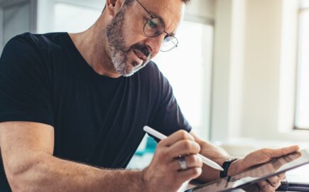 Yrittäjä työskentelee tabletilla toimistoympäristössä – yrittäjän eläkevakuutus turvaa tulevaisuutta ja sosiaaliturvaa.