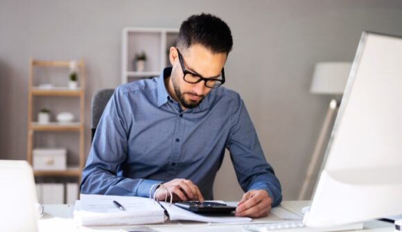 Yrittäjä tarkistaa kirjanpitoa tietokoneella tilanteessa, jossa asiakas ei maksa laskua ja käsiteltävänä on maksamaton lasku.